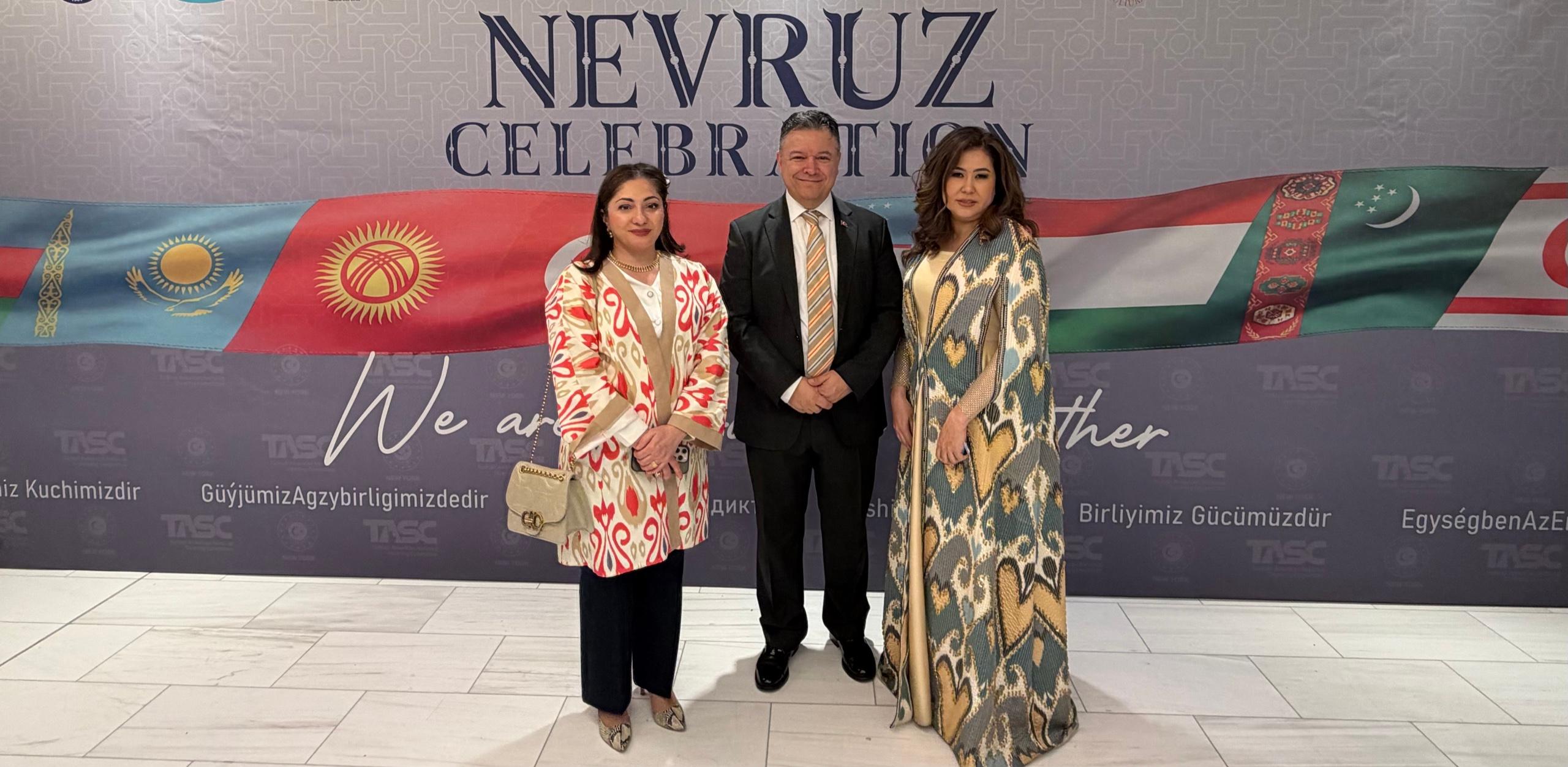 Three guests posing before a Nevruz Celebration backdrop decorated with Central Asian flags